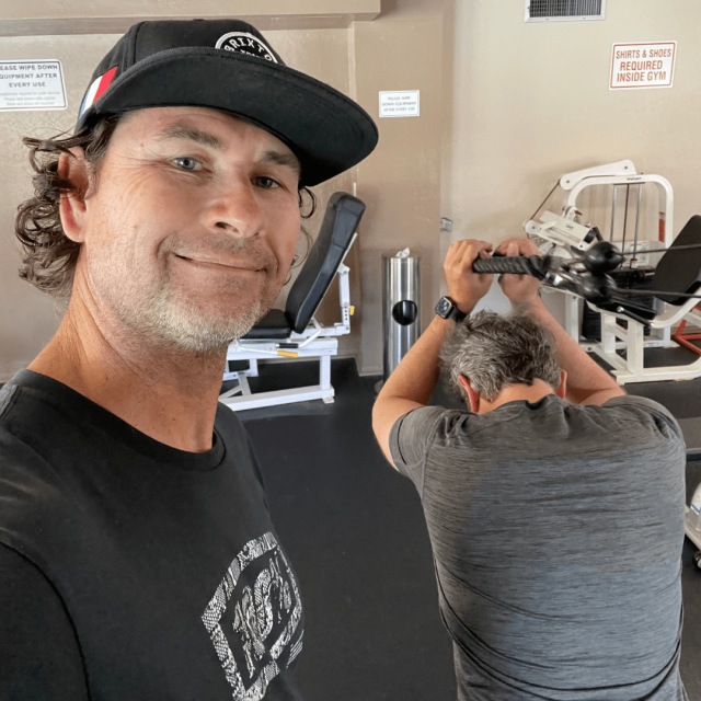 Best trainer in San Diego is smiling while a mid age client is exercising with a rope