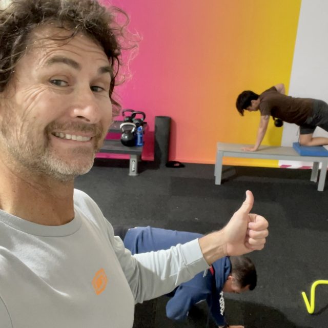 Best Trainer in San Diego giving a thumb up to two male mid age working out 