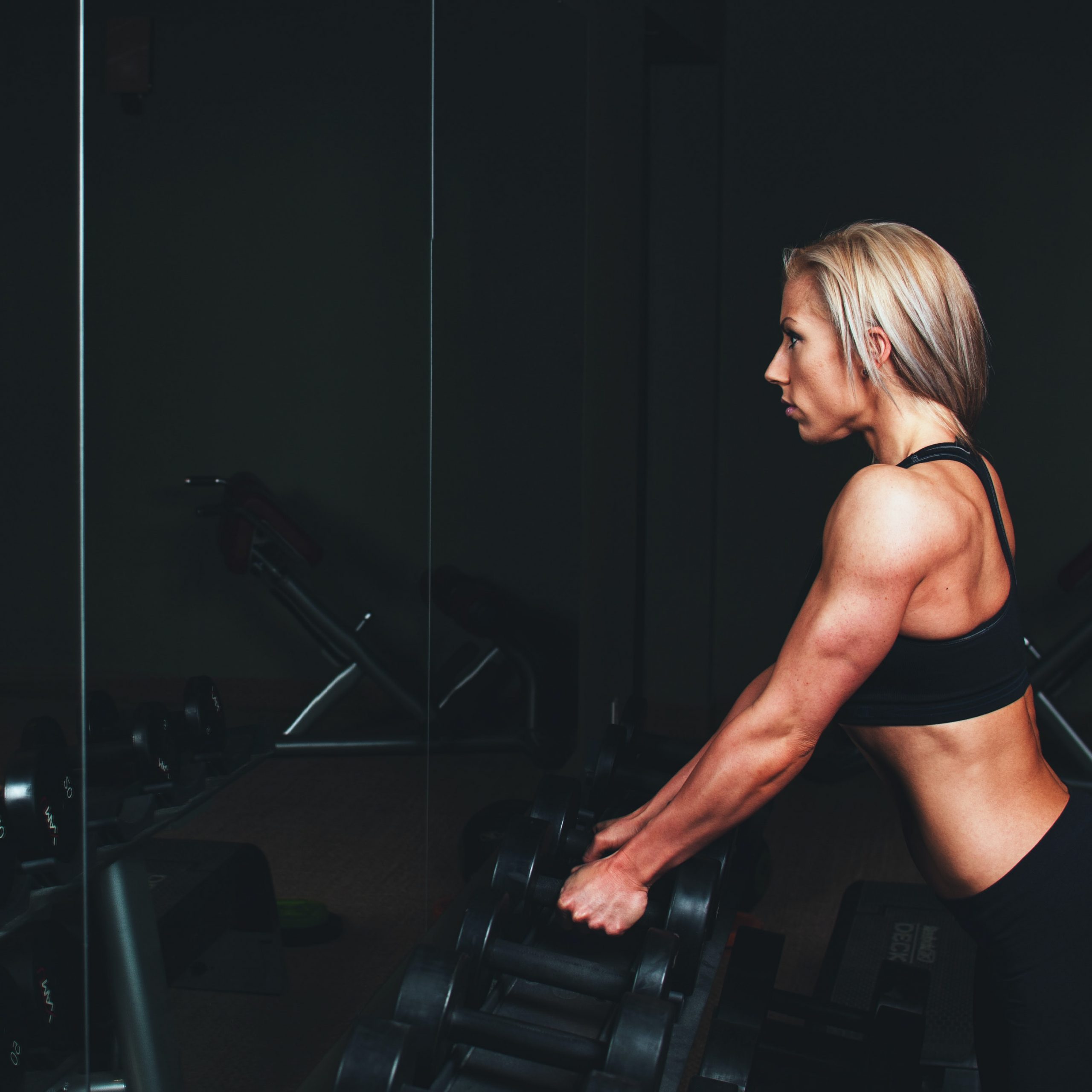 A woman blond in her thirties is taking dumbbells to be fit and strong