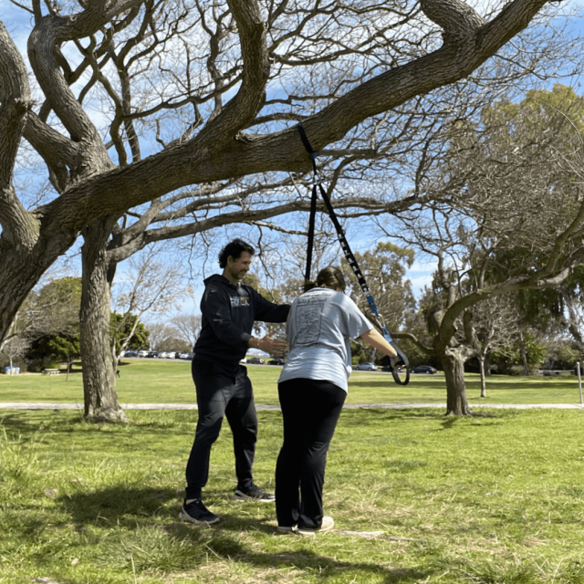 San Diego best personal trainer is coaching a twenty years old client to perform a super slow strength training in a park 