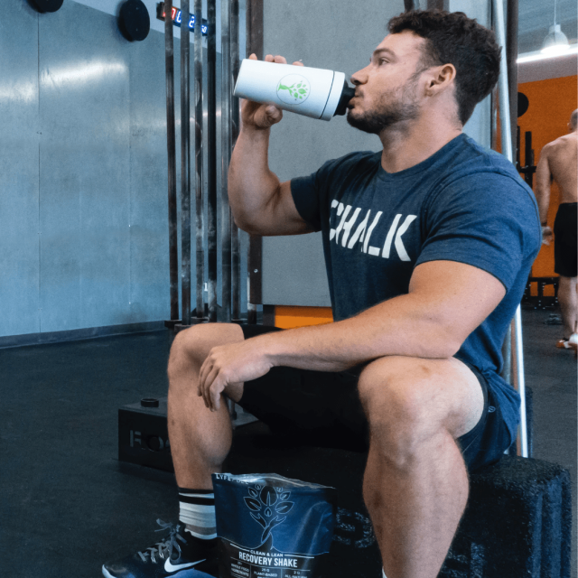 Young man drinking a protein shake in a seat down position inside a gym in La Jolla California
