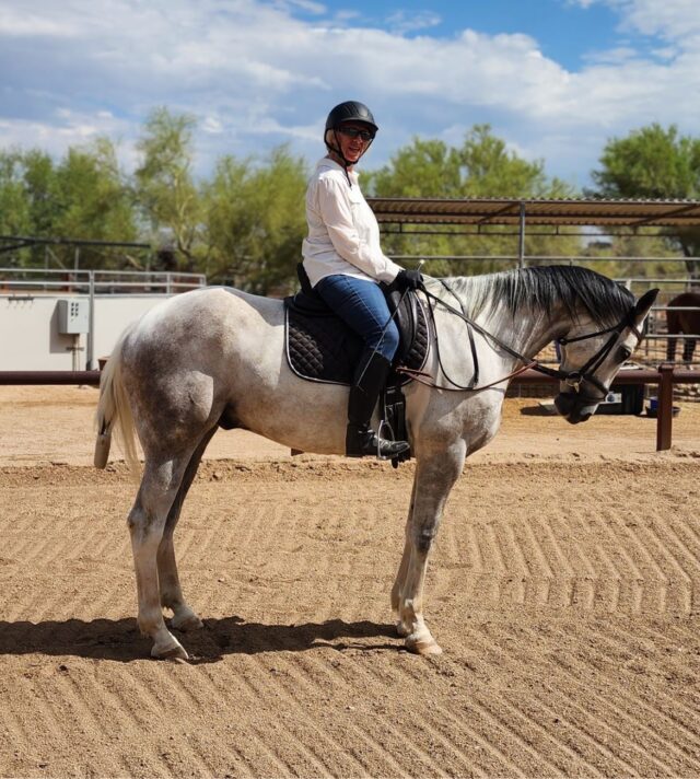 Marsha smiling while riding her horse after recovering from a vertebra fracture through structured personal training and back-strength rebuilding.